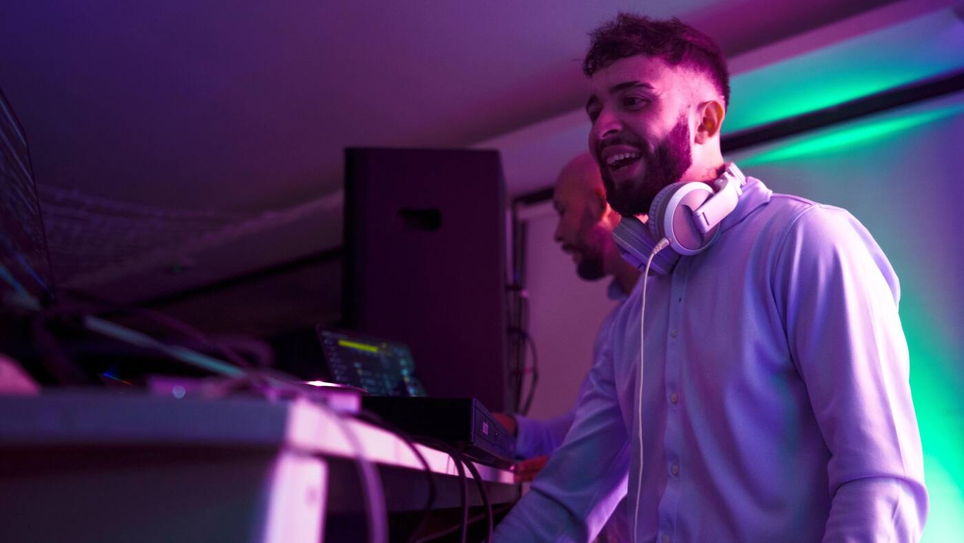 DJ de Paradise Music pinchando con cascos bajo luces violetas